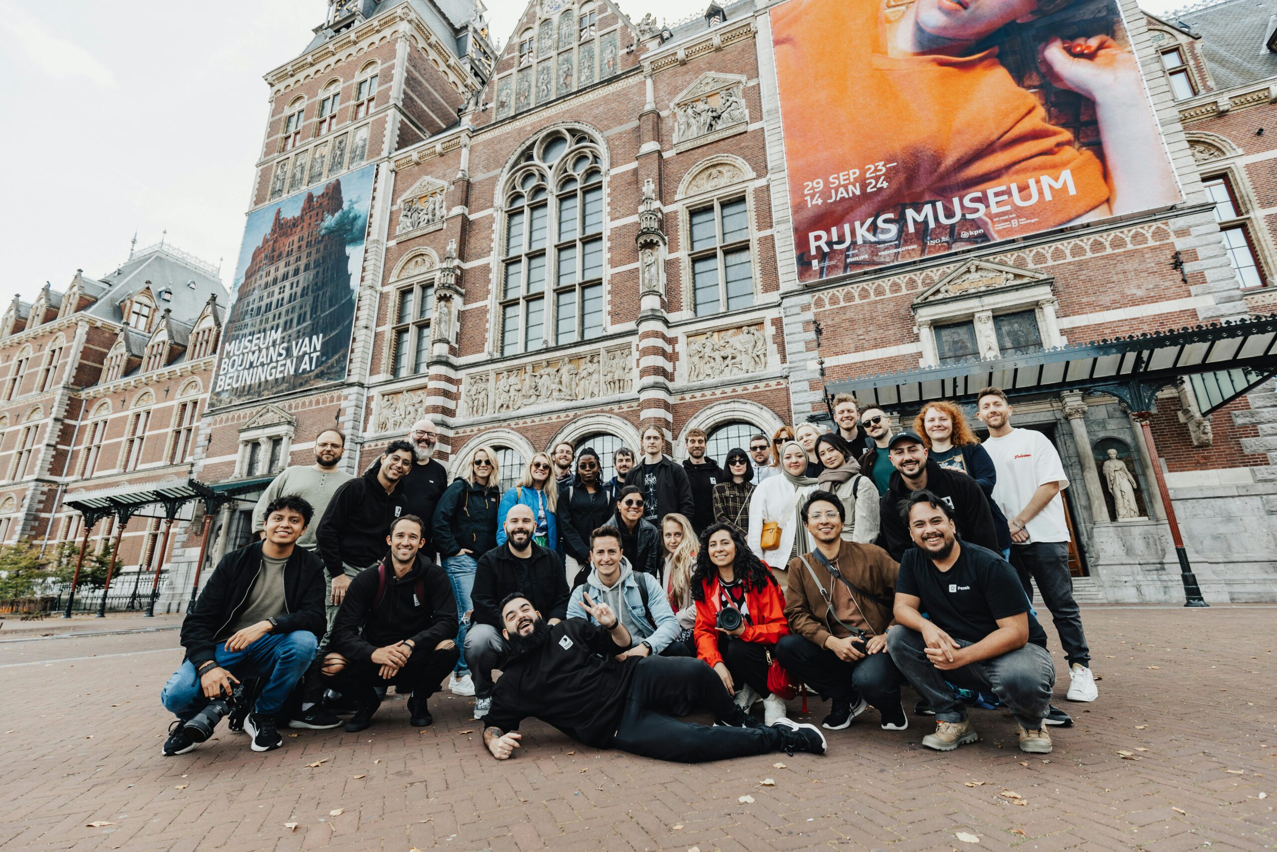 A cheerful group of friends posing in front of the iconic Rijksmuseum in Amsterdam.